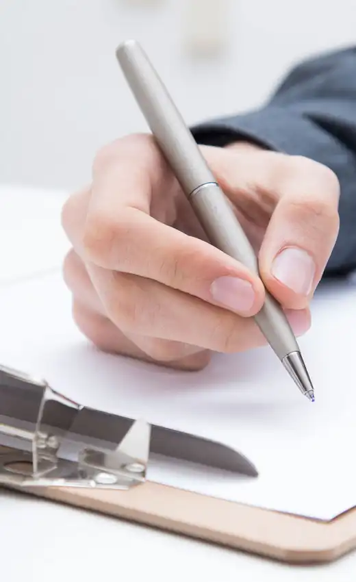 Hand writing with a pen on a clipboard, symbolizing note-taking at the Udana Training Courses Hand writing with a pen on a clipboard, symbolizing note-taking at the Udana Training Courses.